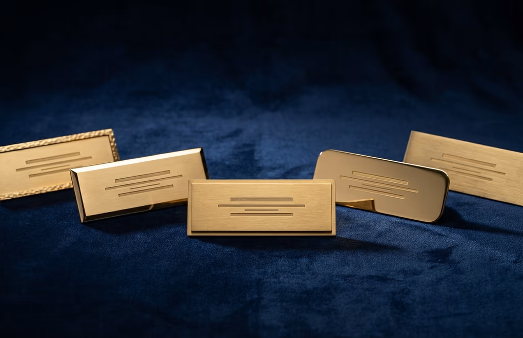 Five engraved brass nameplates for different professional roles on dark velvet