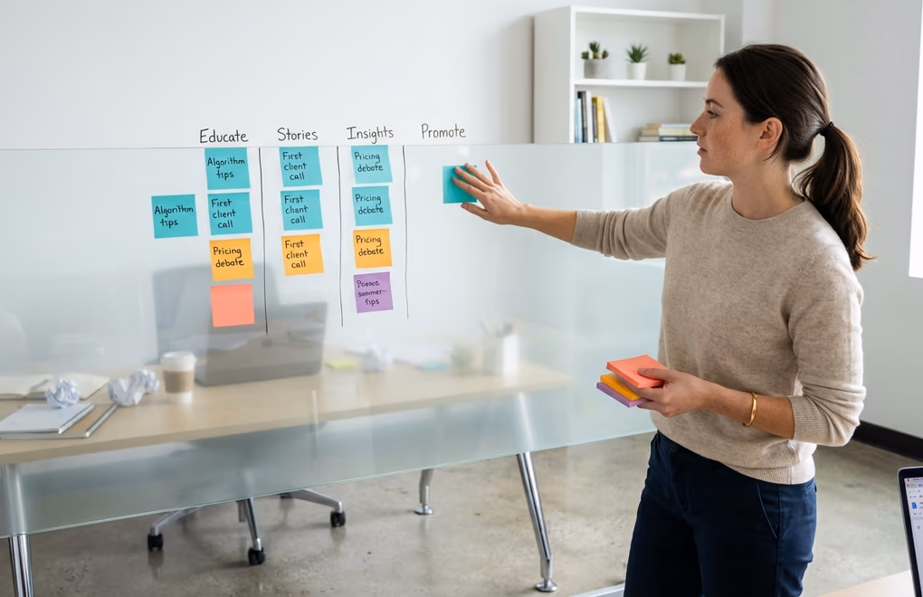 Person organizing colorful sticky notes on a glass wall planned LinkedIn content themes versus a messy desk with